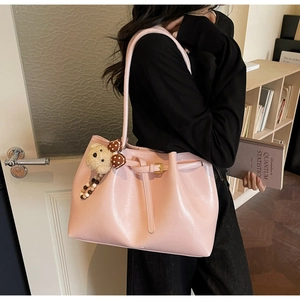 Détail du grand sac cabas rose avec breloque d'ours porté par un mannequin en intérieur