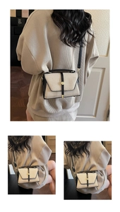Détail d'un sac à main chic en toile crème avec bordure en cuir noir et boucle dorée