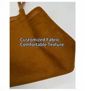Close-up of brown suede shoulder bag showing soft textured fabric and drawstring detail