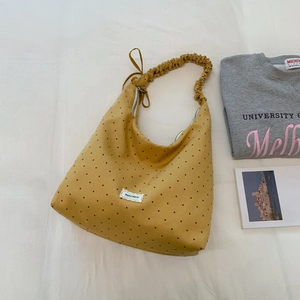 Detail of yellow polka dot canvas bag with white lace label and scrunchie strap design