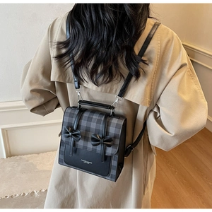 British style grey plaid backpack with leather bow details and adjustable straps on a model