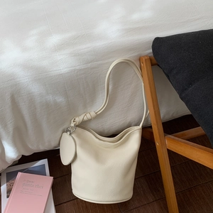 Détail du sac seau blanc crème avec texture grainée et bandoulière à nœud réglable