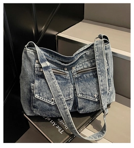 Close-up of vintage blue denim tote with multi-pockets and silver hardware on stone steps