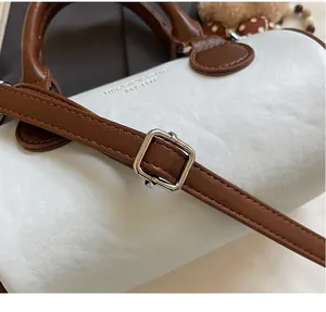 Detailed close-up of adjustable strap buckle on a two-tone leather cylinder handbag