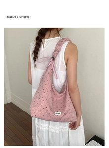Detail of pink polka dot canvas tote with ruffled shoulder strap and white label