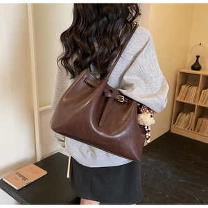Détail d'un cabas vintage en cuir marron avec texture mate et pendentif en peluche