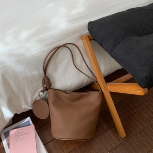 Détail du sac seau en cuir marron foncé avec un petit porte-monnaie rond suspendu