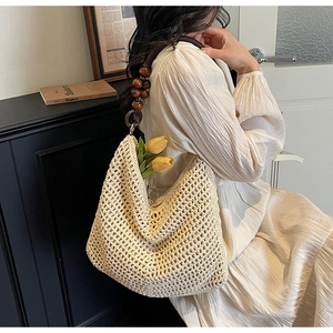 Detail of hand-crocheted cream tote bag with dark brown wood beads on the shoulder strap