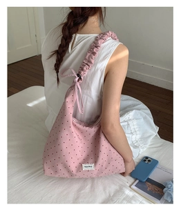 Detail of a pink polka dot canvas tote bag with ruffled drawstring shoulder straps