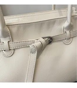 Close-up of white tote bag with crinkled leather texture and silver buckle detail
