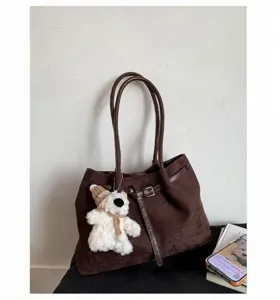 Detailed macro view of dark brown suede tote bag with metal buckle and plush bear charm