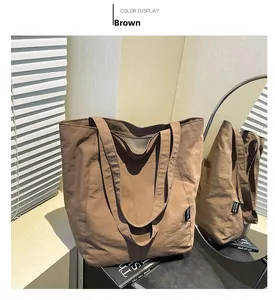 Detail view of brown textured nylon tote bag with wide shoulder straps and striped lining