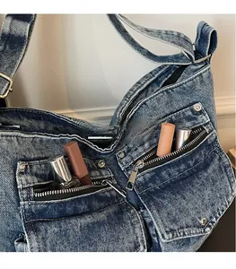 Detail of vintage blue denim tote bag showing multiple functional utility pockets and metal zippers