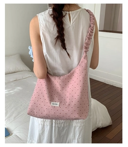 Detail of pink polka dot canvas tote with ruffled shoulder strap worn by a model