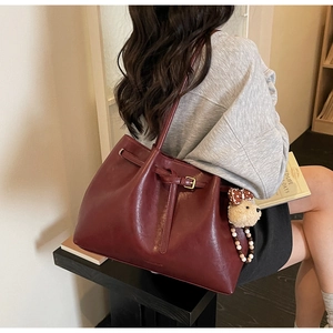 Sac fourre-tout bordeaux vintage avec breloque ours porté à l'épaule par un mannequin