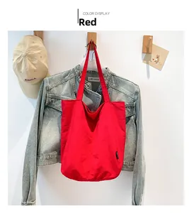 Detail view of large red canvas tote bag hanging on a hook in a casual lifestyle setting