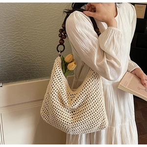 Detail of hand-crocheted cream tote bag with dark wood beads and hollow mesh design