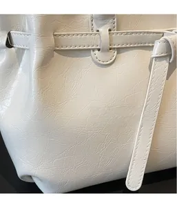 Detailed close-up of off-white wrinkled leather texture and strap buckle on a tote bag
