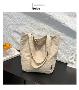 Close-up of beige tote bag made from crinkle fabric on a minimalist display stand