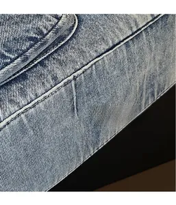 Detail shot of light blue denim fabric with visible twill weave and topstitch on a tote bag