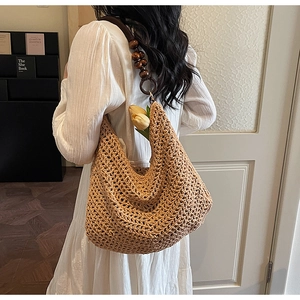 Detail of hand-woven straw hobo bag with dark wooden beads and large grid structure