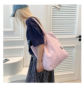 Detail of light pink canvas tote bag showing soft textured fabric and black side label