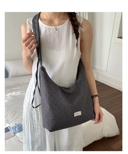 Detail shot of the large dark grey polka dot canvas tote bag with a side woven label
