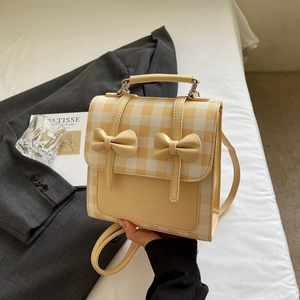 Detail of yellow and white plaid backpack with decorative bows in a lifestyle setting