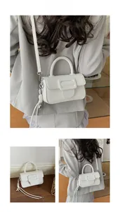 Detail view of white leather crossbody bag with square buckle and adjustable strap