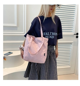 Lifestyle shot of large light pink canvas tote bag carried by a model in casual outfit