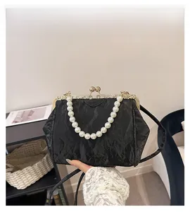 Detail of vintage black pleated handbag with pearl beaded handle and gold metal clasp