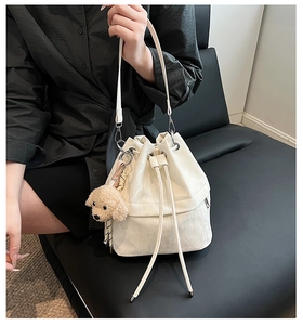 Detailed view of a white drawstring bucket bag with a cute plush dog pendant charm