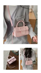 Detail view of pink square crossbody bag with large buckle and detachable strap