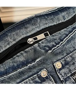 Detail of silver metal zipper and neat stitching on a blue washed denim tote bag