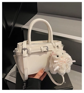 Detailed view of white matte leather handbag with plush bunny charm and silver buckle strap