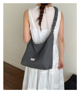 Detail of the dark gray corduroy tote bag featuring pleated straps and a minimalist label
