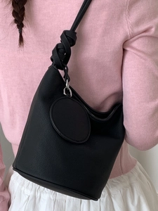 Sac seau minimaliste en cuir noir avec bandoulière à nœud tressé sur un mannequin