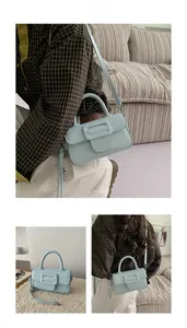 Detail view of light blue PU leather square bag with decorative buckle and woven charm
