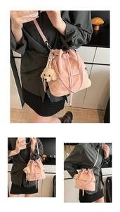Detailed view of pink drawstring bucket bag with a cute plush poodle charm and glossy texture