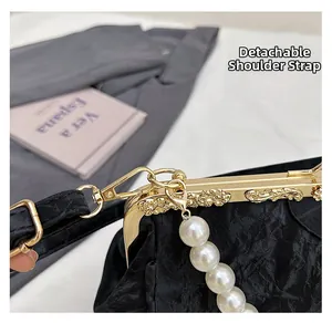 Close-up of black pleated shell bag with vintage gold frame and pearl charm details