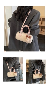 Detail view of a cream and pink Boston bag with a cute plush bear charm and adjustable strap
