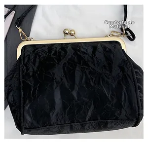 Close-up of black pleated fabric and golden metal clasp on vintage evening handbag