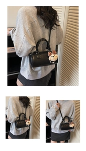 Detail of vintage black cylindrical pillow bag featuring a cute plush bear charm