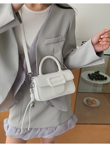 Close-up of a white leather crossbody bag with a large square buckle on the front flap