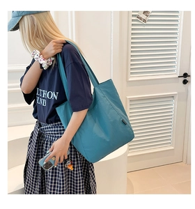 Detailed close-up of a minimalist teal tote bag side with black logo label detail