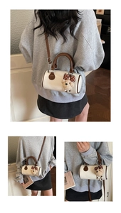 Close-up of white Boston bag featuring a plush bear charm with polka dot bow detail