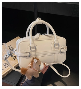Detail of cream white leather boston bag with twin handles and cute horse charm
