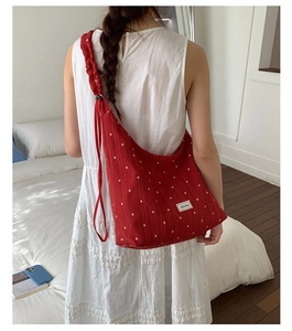 Detail of red floral tote bag with white flower pattern and ruffle strap design