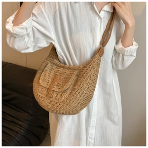 Detail of a beige woven straw hobo bag featuring brown leather trim and shoulder strap