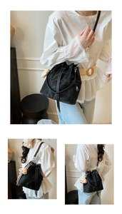 Detail of black drawstring bucket bag with textured fabric and plush bear pendant